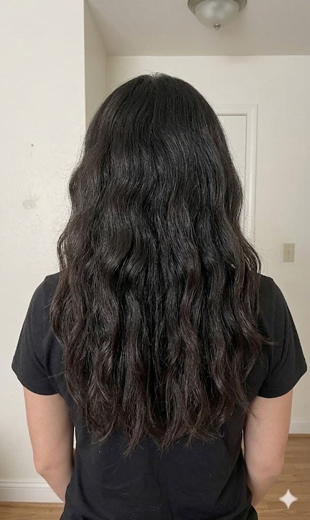 An "After" photo of the same person from behind, showing long, dark, wavy hair that is now smooth, glossy, and highly defined. The frizz is gone, and the waves look hydrated and healthy with a noticeable high-impact shine.
