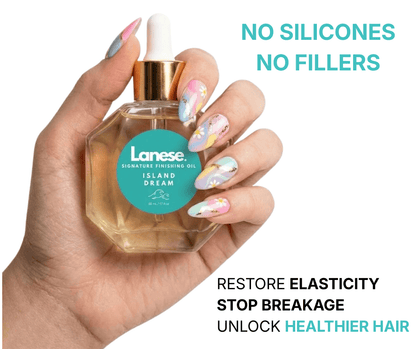 A close-up of a person’s hand with colorful floral and swirl-patterned nail art holding a hexagonal glass bottle of Lanese Island Dream Signature Finishing Oil. The label is bright teal with a wave icon. Text to the right and below reads: "No Silicones, No Fillers. Restore elasticity, stop breakage, unlock healthier hair."