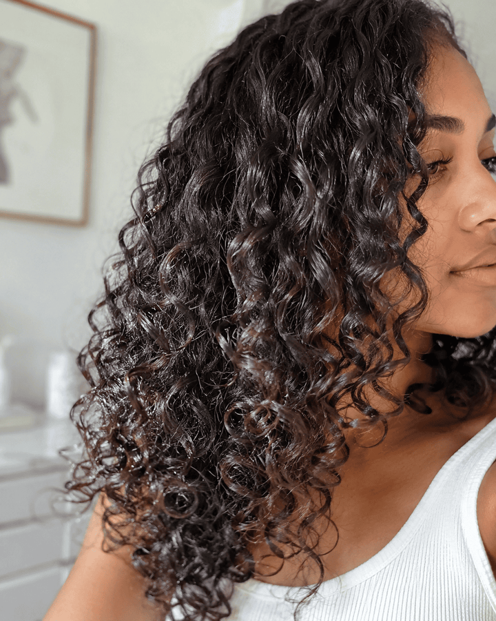 Woman with curly hair in a neutral indoor setting