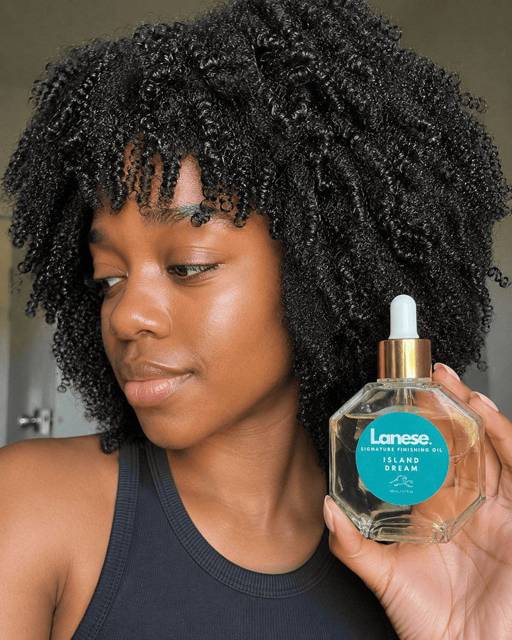 Person holding a bottle of Lanese hair oil with a neutral background