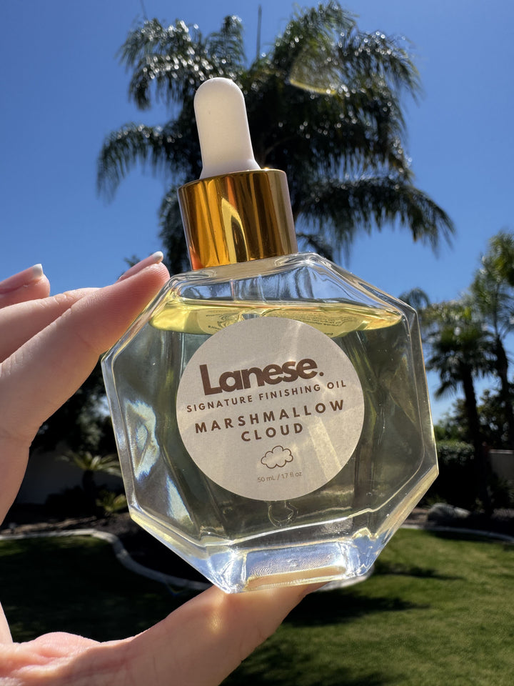 Lanese Marshmallow Cloud oil bottle held in hand with palm trees in the background