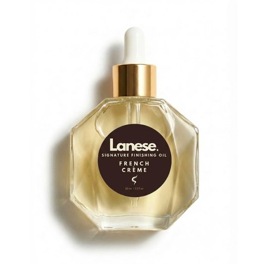 A hexagon-shaped glass dropper bottle of Lanese hair oil with a gold collar and white dropper bulb, set against a plain white background. The dark brown label reads: "Lanese. SIGNATURE FINISHING OIL. FRENCH CRÈME. 50 mL / 1.7 fl oz".