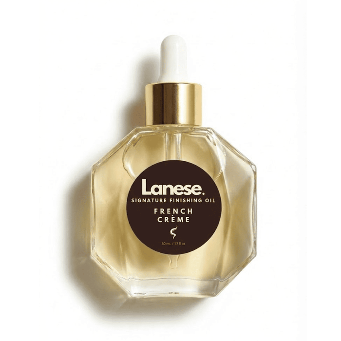 A studio product shot of the Lanese Signature Finishing Oil in French Crème. The hexagonal glass bottle has a gold cap and a white dropper top, casting a soft shadow on a white background.