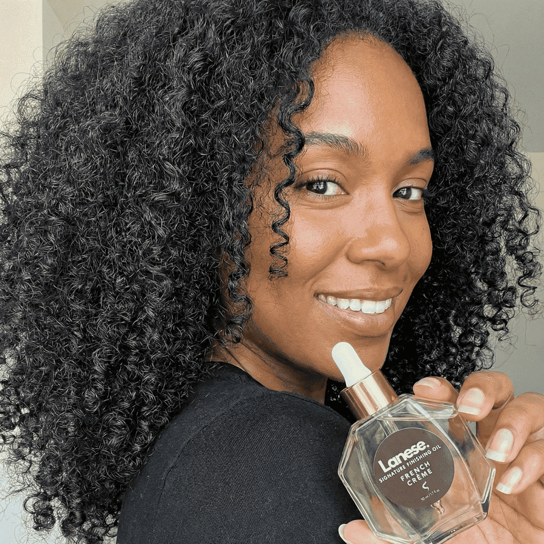 Woman holding a Lanese hair oil bottle with a neutral background