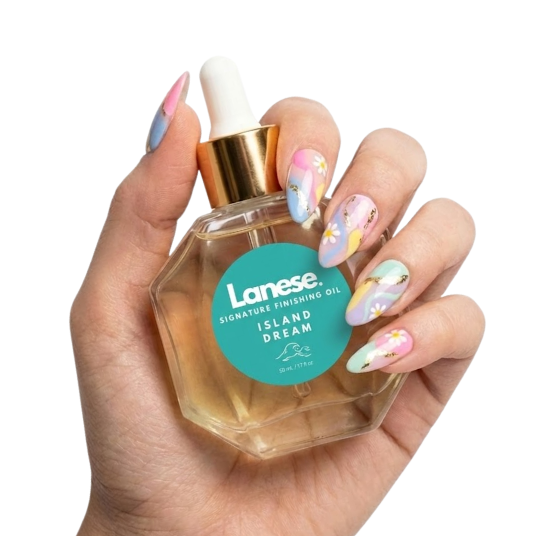 A hand with pastel floral nail art holding a hexagon-shaped glass dropper bottle of Lanese hair oil against a white background. The teal label on the bottle features a small wave icon and reads: "Lanese. SIGNATURE FINISHING OIL. ISLAND DREAM. 50 mL / 1.7 fl oz"